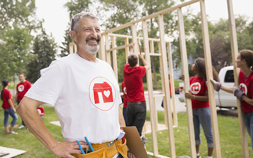 senior man volunteering and building houses